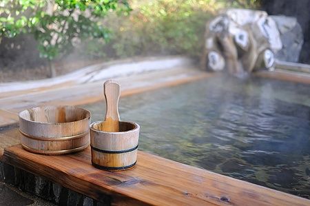 Vasca termale all'aperto in un ryokan giapponese con secchi in legno.