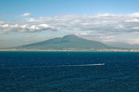 Vista del Vesuvio e Napoli dal mare a Sorrento con cielo parzialmente nuvoloso.