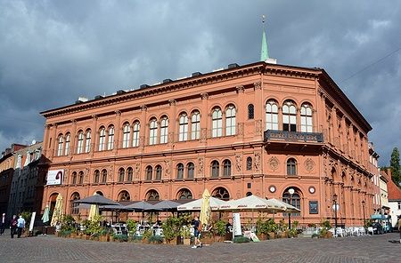 Art Museum Riga Bourse a Riga con cielo nuvoloso e persone sullo sfondo.