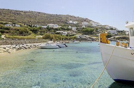 Barche da pesca ormeggiate a Ornos, Mykonos, con case bianche sullo sfondo.