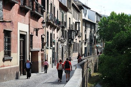 Edifici lungo la Carrera del Darro con persone che camminano a Granada.