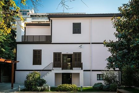 Casa bianca con persiane marroni a Salonicco, Grecia sotto il sole.