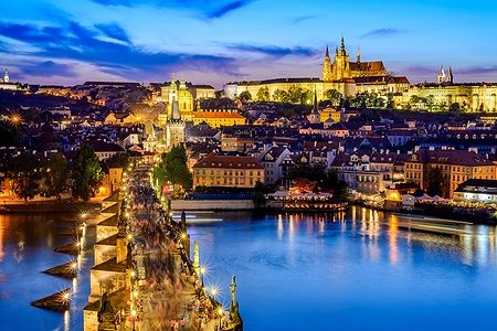 Vista serale del Castello di Praga e del Ponte Carlo illuminati.