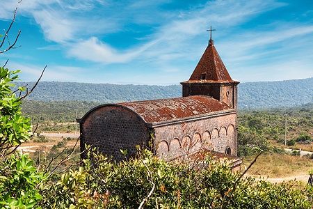 Chiesa cristiana abbandonata sul monte Bokor, circondata da natura lussureggiante.