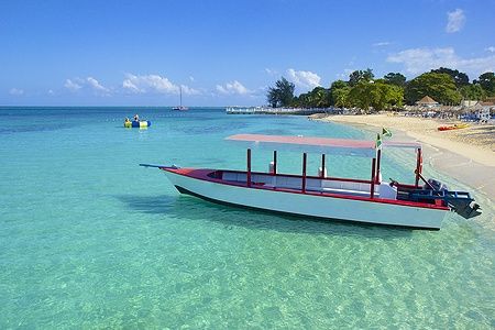 Barca ancorata in acque turchesi vicino a Doctor's Cove Beach a Montego Bay, Giamaica.