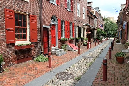 Strada storica di Elfreth's Alley a Philadelphia, con case in mattoni e persiane rosse.