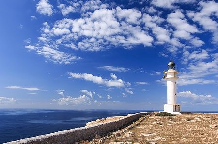 Faro bianco a Formentera, Spagna, con cielo blu e nuvole.