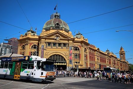 Tram di fronte a Flinders Street Station a Melbourne con folla attraversando.