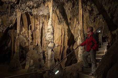 Un uomo osserva stalattiti illuminate nella grotta Szent Istvan, Ungheria.