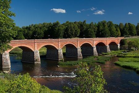 Ponte di Kuldiga in mattoni rossi sul fiume in una giornata soleggiata.