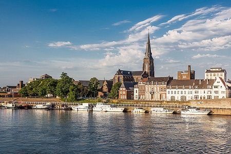 Lungofiume di Maastricht con imbarcazioni e architettura storica.