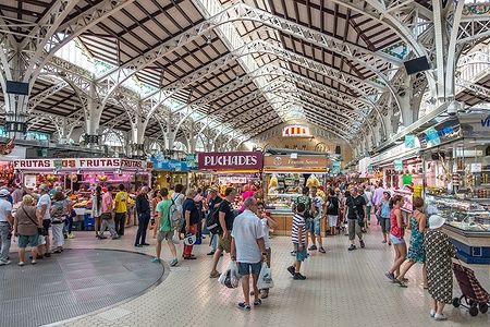 Persone che fanno shopping al Mercato Centrale di Valencia, circondati da bancarelle colorate.