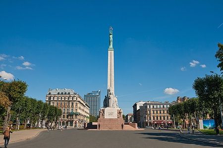 Il Monumento alla Libertà a Riga con edifici storici e cielo blu.