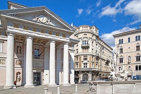 Palazzo della Borsa Vecchia a Trieste con cielo blu e sculture.