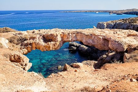 Ponte naturale a Cavo Greco, con acque turchesi del Mediterraneo.
