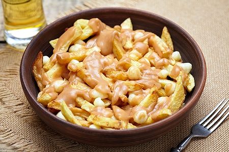 Piatto di poutine canadese con patatine, formaggio e salsa gravy.