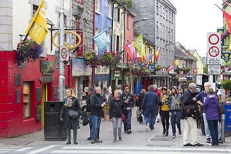 Persone passeggiano lungo Quay Street a Galway, Irlanda, circondate da edifici colorati.