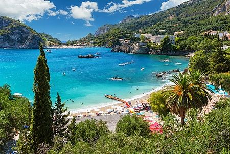 Spiaggia di Paleokastritsa a Corfù con acqua cristallina e vegetazione lussureggiante.