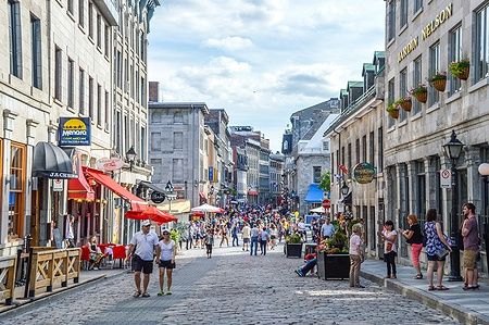 Via affollata di St Paul a Montreal con persone che passeggiano tra edifici storici.