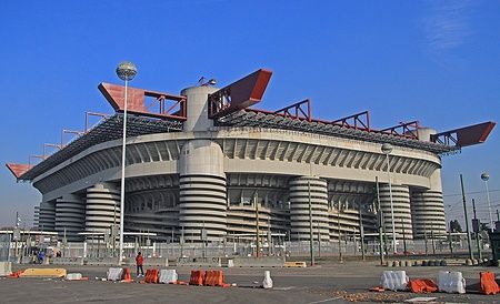 Vista esterna dello Stadio Giuseppe Meazza a Milano sotto un cielo azzurro.
