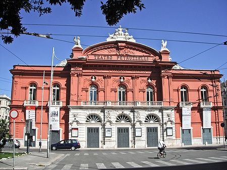 Facciata del Teatro Petruzzelli a Bari con un uomo in bicicletta davanti.