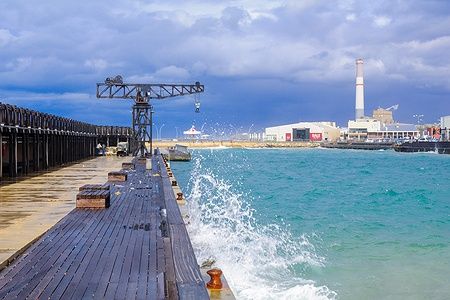 Una gru restaurata a Tel Aviv Port con ristoranti sullo sfondo.