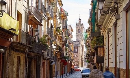 Strada di Valencia con edifici storici e una chiesa sullo sfondo nel Barrio del Carmen.
