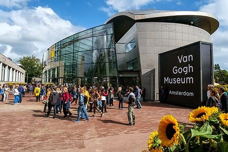 Folla davanti al Van Gogh Museum di Amsterdam con girasoli in primo piano.