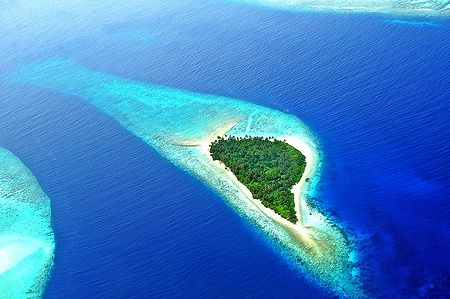 Isola verde circondata da acque blu nell'Addu Atoll delle Maldive.