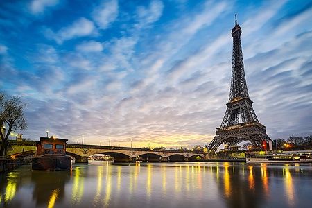 Torre Eiffel a Parigi all'alba con riflessi nel fiume Senna.