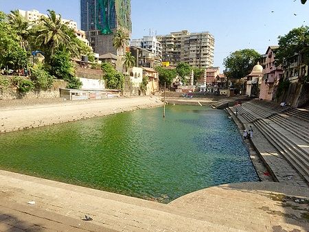 Banganga Tank a Mumbai con gradini e edificio sullo sfondo.