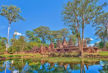 Tempio Banteay Srei a Siem Reap, immerso nella natura con riflessi sull'acqua.
