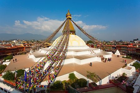 Boudhanath Stupa a Kathmandu con bandiere di preghiera sotto un cielo azzurro.