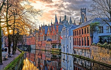 I canali di Bruges al tramonto in una serata invernale con edifici storici riflessi nell'acqua.