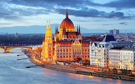 Il Parlamento di Budapest illuminato di notte lungo il Danubio.