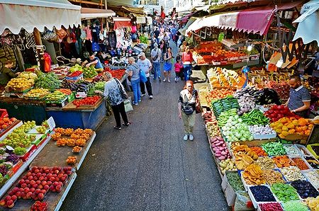 Mercato Carmel Market Shuk HaCarmel a Tel Aviv con bancarelle di frutta e verdura e folla di persone.