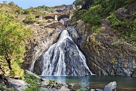 Le cascate Dudhsagar a Goa scorrono tra le rocce sotto un ponte.