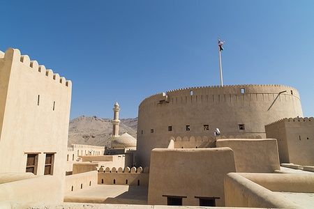 Fort Nizwa in Oman con minareto e cupola della moschea sullo sfondo.