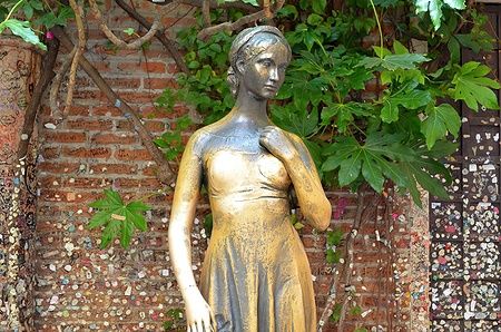 Statua in bronzo di Giulietta nel cortile veronese, simbolo d'amore.