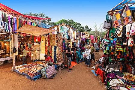 Mercato notturno di Goa con tessuti colorati e persone che esplorano.