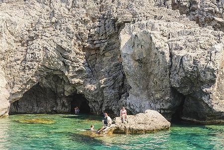 Persone nuotano e si rilassano tra le rocce nel Golfo di Afandou, Rodi.