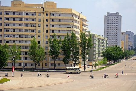 Edifici residenziali a Kaesong, Corea del Nord, con persone in bicicletta.