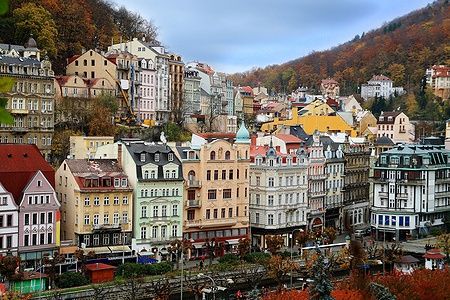 Vista panoramica di edifici colorati a Karlovy Vary circondati da colline autunnali.
