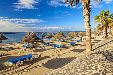 Spiaggia di Los Cristianos a Tenerife con ombrelloni e lettini sotto il sole.