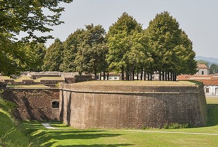 Mura medievali di Lucca circondate da alberi sotto un cielo blu.