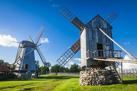 Mulini a vento di legno ad Angla, Saaremaa, Estonia, su prato verde sotto cielo blu.