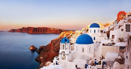 Panoramica su Oia con le iconiche cupole blu al tramonto, Santorini.