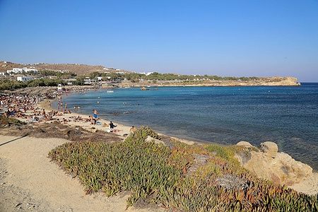 Spiaggia affollata a Paraga Beach, Mykonos, Grecia, con bagnanti e mare azzurro.