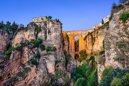 Il Puente Nuevo a Ronda, Spagna, al tramonto con il cielo blu.