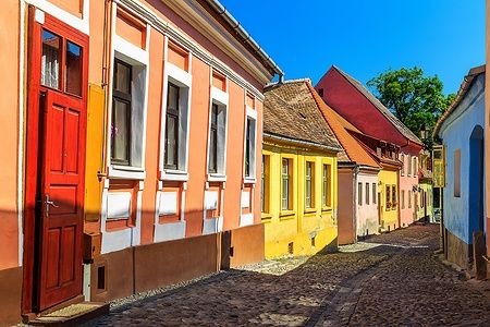 Strada di Sighisoara con case colorate e pavimentazione in pietra.